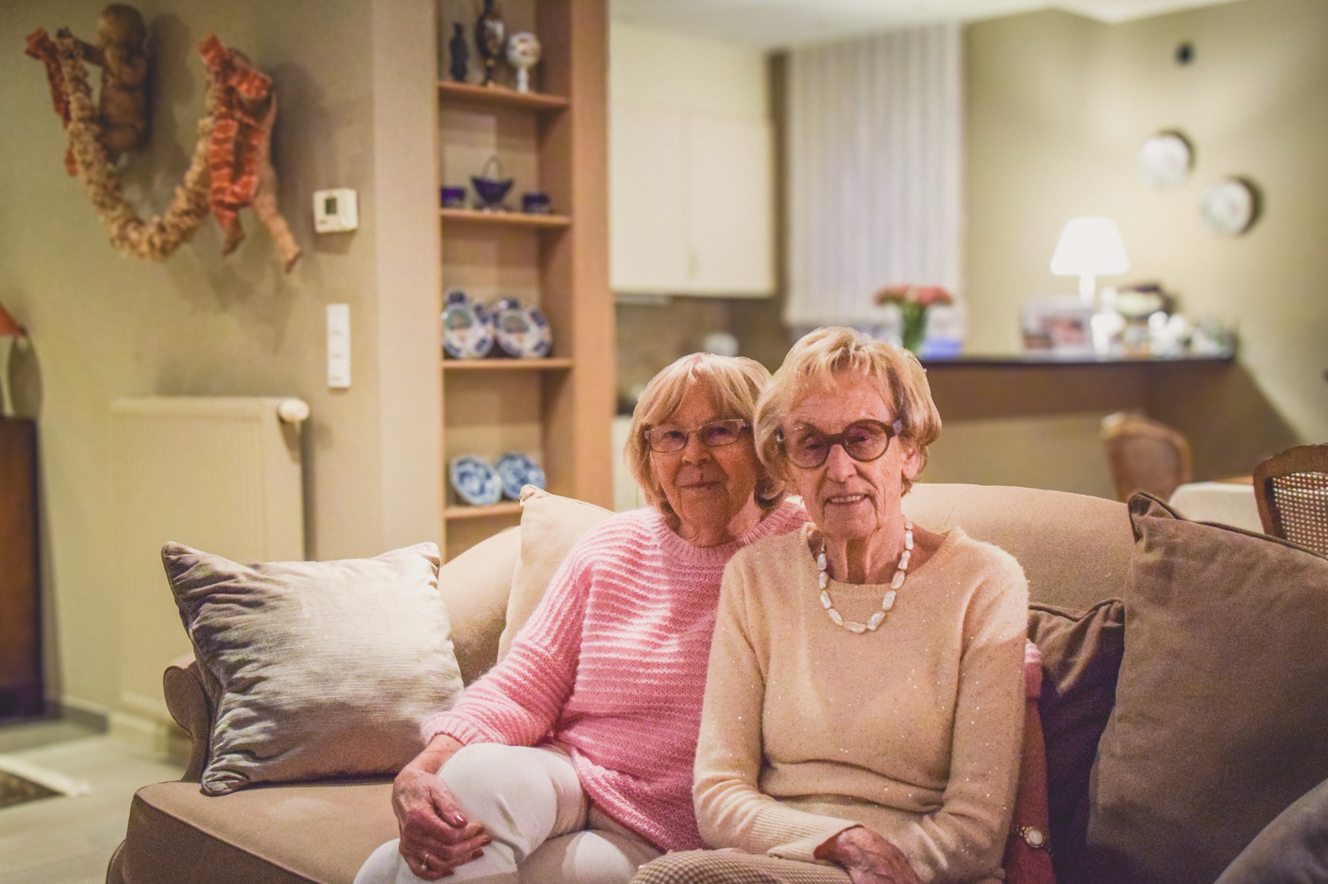 Twee vrouwen zittend op een zetel in een woonkamer